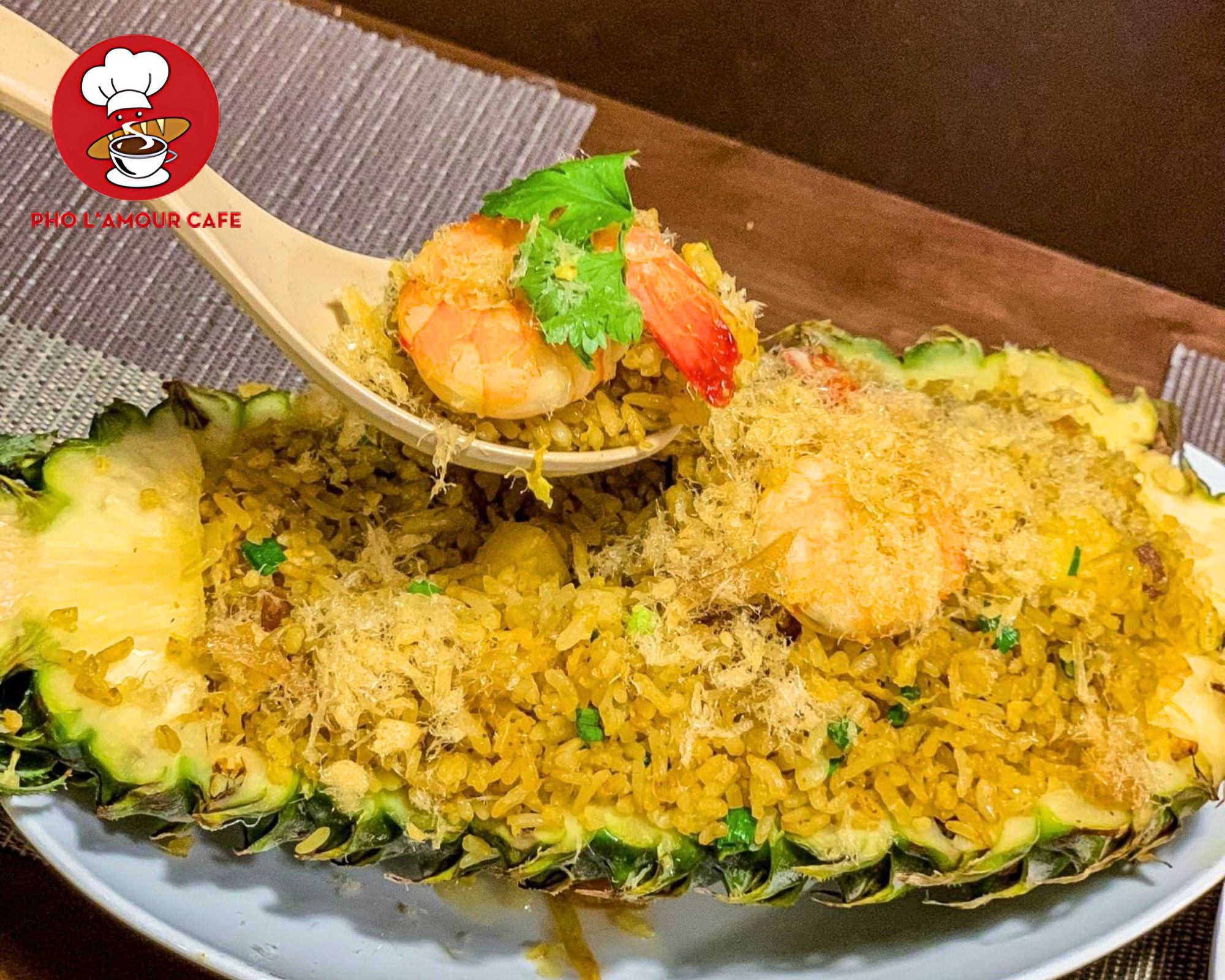 Enjoying a spoonful of fragrant pineapple seafood fried rice topped with a large grilled shrimp and fresh cilantro